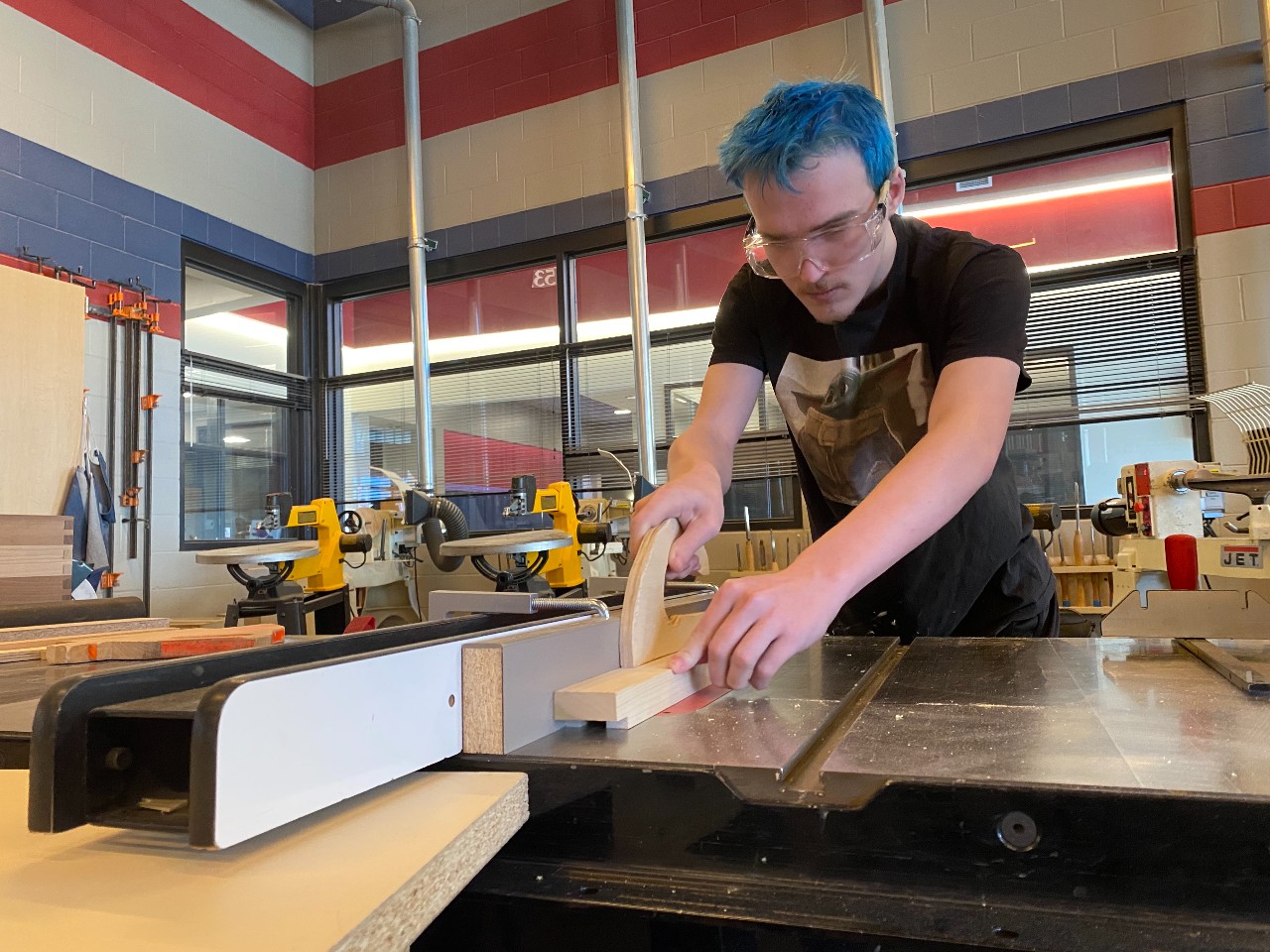 A Liberty High School students cuts wood using a commercial saw in a Career and Technical Education class
